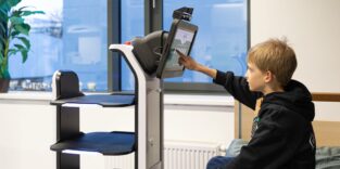 kleiner Junge berührt Display einer Roboterplattform
