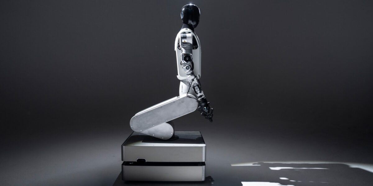Weißer knieender Roboter vor schwarzem Hintergrund