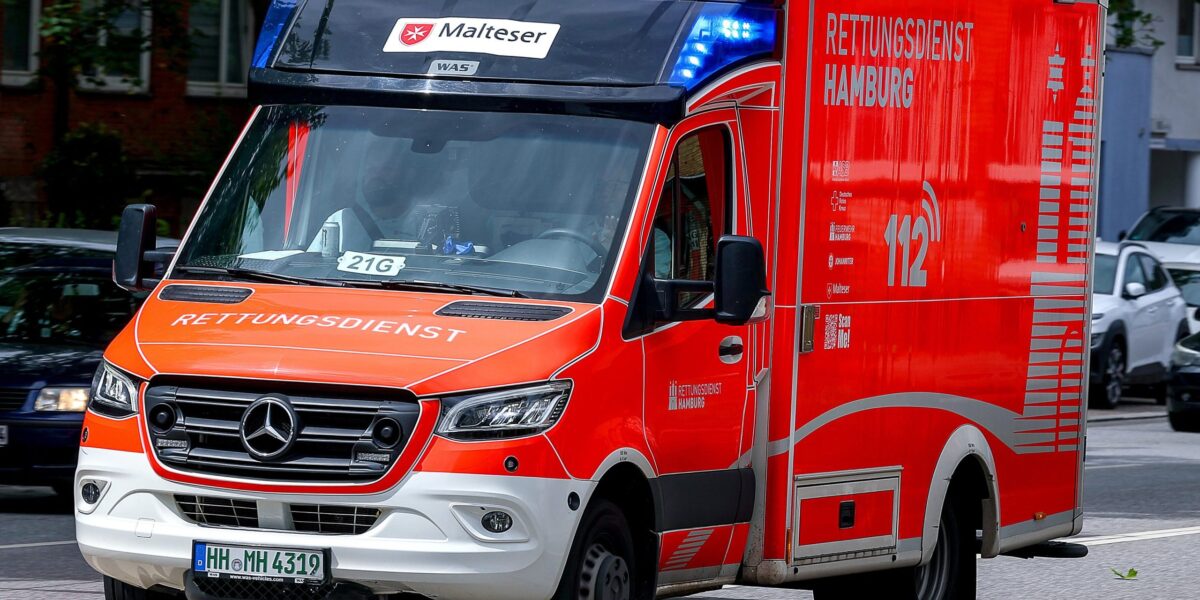 Ein orange-weißer Rettungswagen ist auf einer Straße.