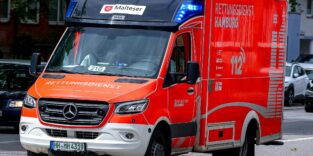 Ein orange-weißer Rettungswagen ist auf einer Straße.