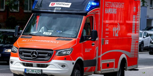 Ein orange-weißer Rettungswagen ist auf einer Straße.