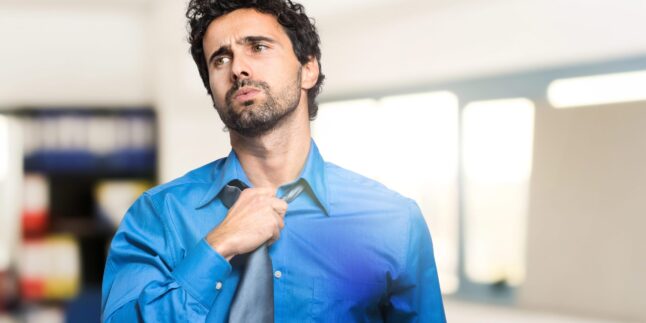 Mann mit Krawatte schwitzt im Büro