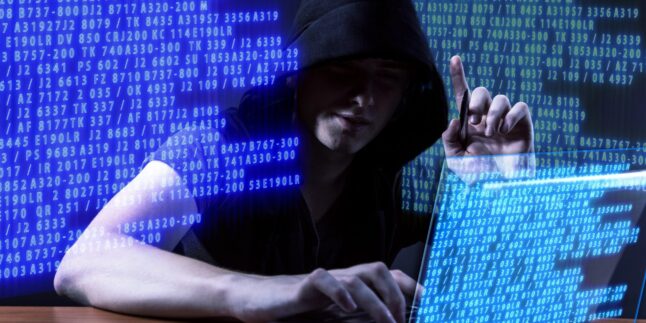 Mann mit Kapuze sitzt vor einem Notebook