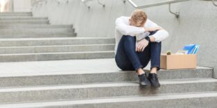 Ein mann sitzt auf der Treppe - er wurde eben gekündigt.