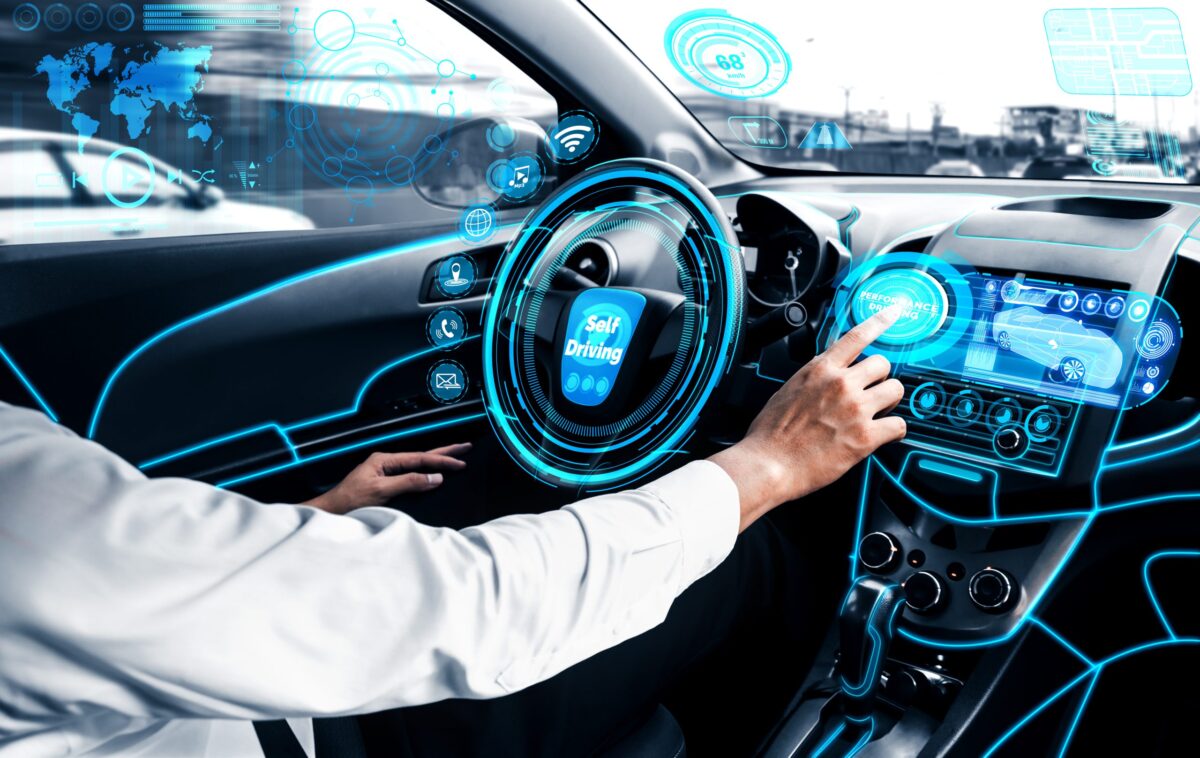 Fahrer in automatisiertem Fahrzeug blickt auf digitale Steuerelemente.