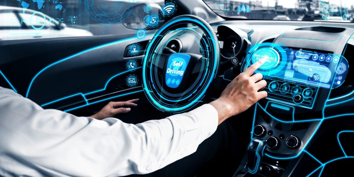 Fahrer in automatisiertem Fahrzeug blickt auf digitale Steuerelemente.