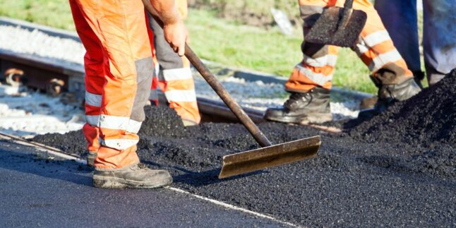 Bauarbeiter verteilen Asphalt