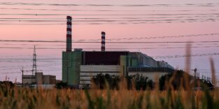 Ungarisches Atomkraftwerk Paks, im Vordergrund ein Feld am Himmel viele Stromleitungen