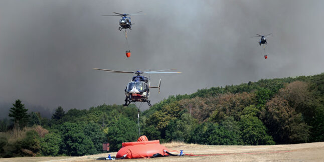 Helikopter fliegen an, um Wasser in Löschwasser-Außenlastbehältern zum Einsatz beim Waldbrand im Hürtgenwald aufzunehmen