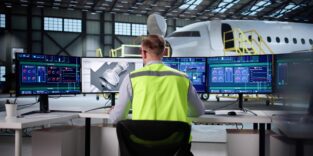 Luft- und Raumfahrtingenieur entwickelt Software für die Flugzeugfertigung auf seinem Desktop-PC. Passagierflugzeug im Hintergrund.