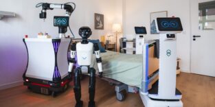 Man sieht verschiedene Roboter, humanoid und auf Plattformen in einem Pflegezimmer.