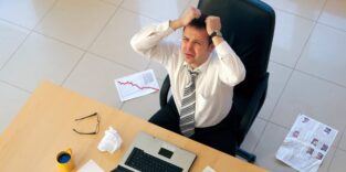 Mann rauft sich die Haare am Schreibtisch