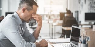Mann reibt sich Augen vor PC