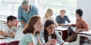 Lehrer in Klasse mit Schülern am Laptop