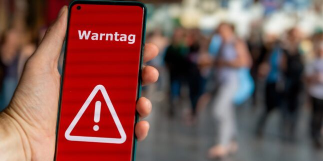 Smartphonenutzer mit Hinweis „Warntag“ auf dem Display