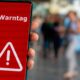 Smartphonenutzer mit Hinweis „Warntag“ auf dem Display
