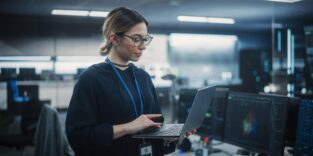 Frau steht und hat Laptop in der Hand