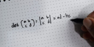Hand schreibt mathematische Formel auf Notizblock