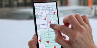 Frauenhand tippt auf Smartphone mit Navigation.