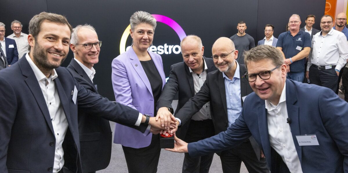 Sechs Personen drücken gemeinsam einen roten Buzzer vor einer Wand mit Covestro-Logo