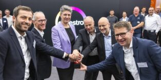 Sechs Personen drücken gemeinsam einen roten Buzzer vor einer Wand mit Covestro-Logo
