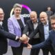 Sechs Personen drücken gemeinsam einen roten Buzzer vor einer Wand mit Covestro-Logo