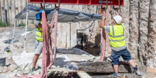 Ein bis zu 250 kg schwerer Eichenbalken wird vorsichtig aus der Baugrube am Aschaffenburger Mainufer gehoben