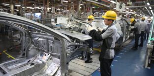 Menschen in der Automobilproduktion bauen Blechteile an Karosserie