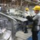 Menschen in der Automobilproduktion bauen Blechteile an Karosserie