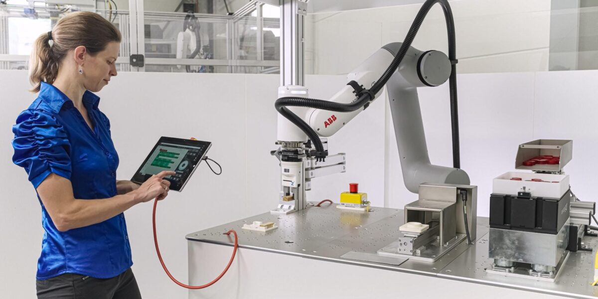 Frau programmiert Roboter via Tablet.