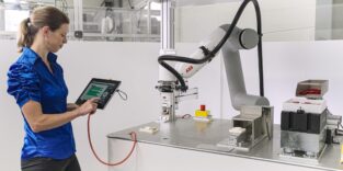 Frau programmiert Roboter via Tablet.