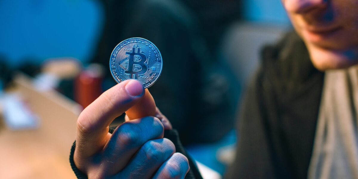 Mann hält Bitcoin-Münze in der Hand