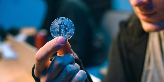 Mann hält Bitcoin-Münze in der Hand