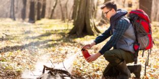 Mann löscht Feuerstelle im Wald mit Feuerlöscher