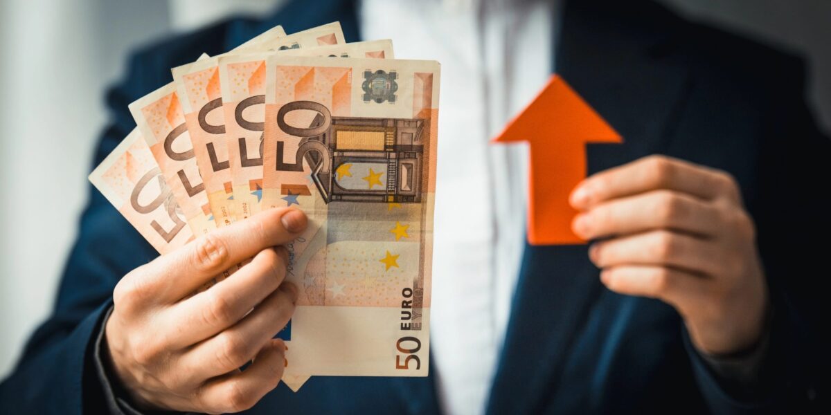 Geschäftsperson hält Euro-Scheine und einen roten Pfeil.