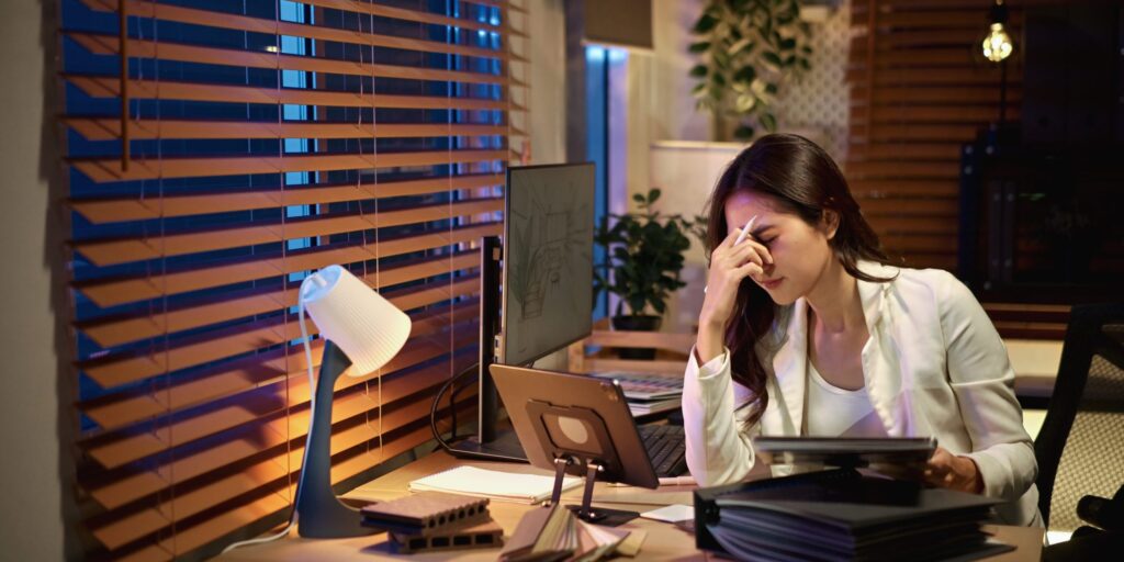 Frau sitzt müde am Arbeitstisch.