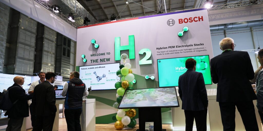 Messestand von Bosch auf der Hydrogen Technology Expo 2026 in Hamburg mit großem H2-Schriftzug, Luftballons in Grün und Weiß und mehreren Besuchern vor Bildschirmen.