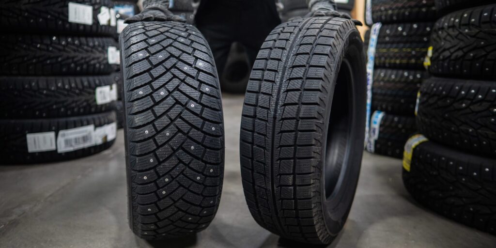 Mechaniker lagert neue Sommer- und Winterreifen in der Werkstatt. Vergleich von Rädern für verschiedene Jahreszeiten.