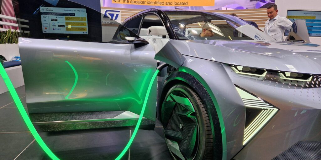 Futuristisches silbernes Elektro-Konzeptfahrzeug mit grüner LED-Beleuchtung auf einem Messestand.