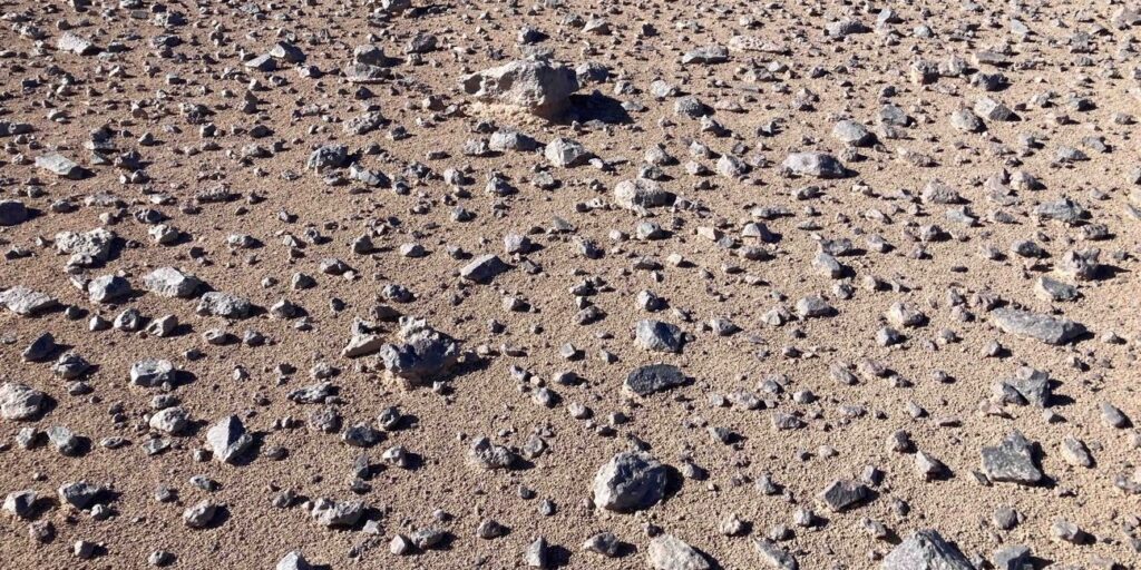 Steiniger, trockener Wüstenboden in der Atacama-Wüste mit Sand, Kies und verstreuten Felsbrocken.
