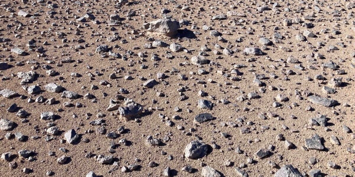 Steiniger, trockener Wüstenboden in der Atacama-Wüste mit Sand, Kies und verstreuten Felsbrocken.