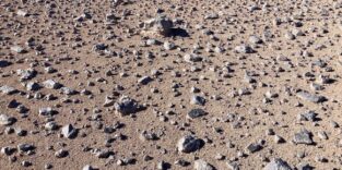 Steiniger, trockener Wüstenboden in der Atacama-Wüste mit Sand, Kies und verstreuten Felsbrocken.