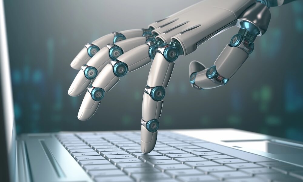 Roboterhand tippt mit einem Finger auf einer Notebook-Tastatur.
