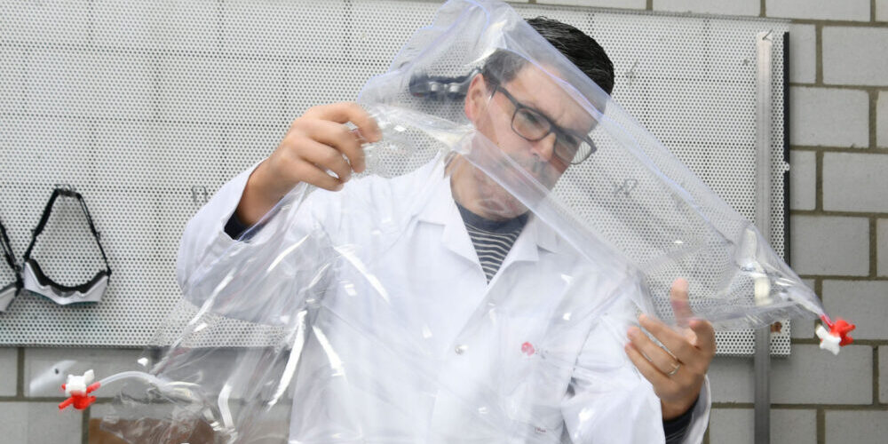 Forschender hält Prototyp einer Matratze für Neugeborene mit Sensoren in der Hand.