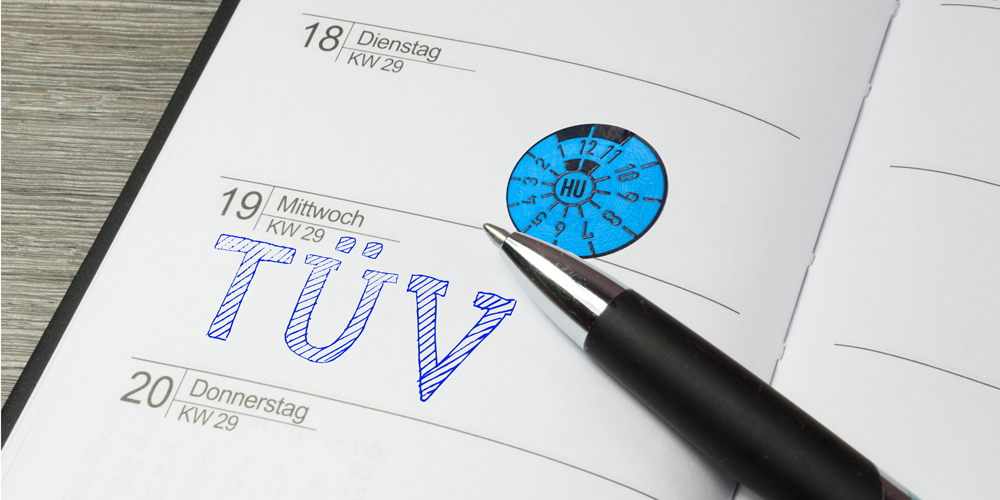 Ein aufgeschlagener Kalender mit dem Vermerk "TÜV" und einer TÜV-Plakette