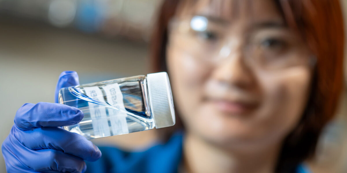 Forscherin hält eine Flasche mit dem wasserbasierten, fluorfreien Binder für Lithium-Ionen-Batterien in der Hand.