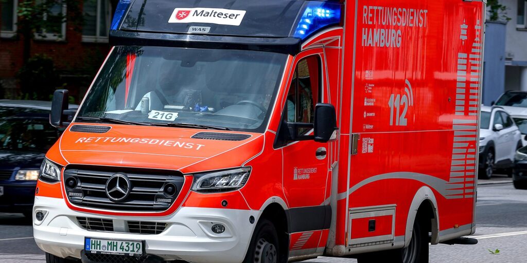 Ein orange-weißer Rettungswagen ist auf einer Straße.