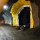 Beschäftigter in Warnkleidung im Rogfast-Tunnel; seitliche Öffnungen mit gelben und weißen Folien sowie eine Lüftungsleitung unter der Decke.