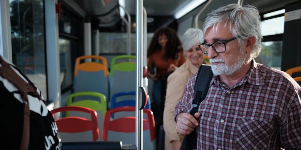 Älterer Mann mit Rucksack steigt aus dem Bus
